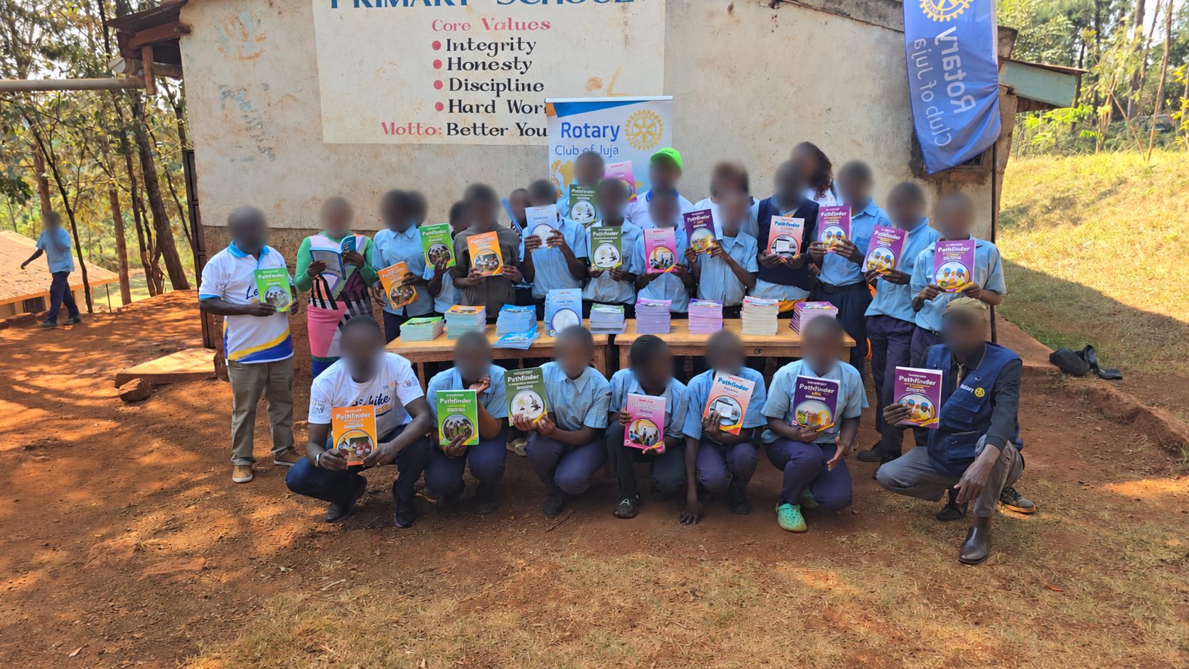 Pupils and club members holding donated books, with faces blurred for privacy